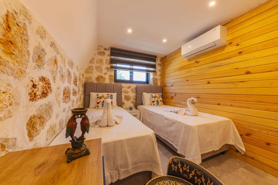 Charming hotel room featuring cozy twin beds, decorative swan towels, and rustic wooden walls.